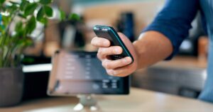 Hand, fintech and a waiter in a coffee shop closeup for sale, payment or purchase of an order. Busi